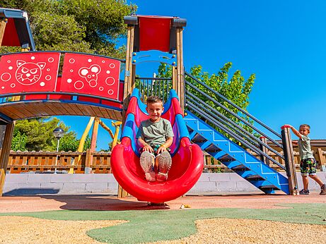Kleurrijke glijbaan en speeltuin met lachende kinderen op camping CAPFUN Alba in CREIXELL (43).