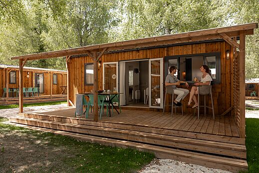 Modern stacaravan met houten terras en barhoek op camping CLICOCHIC Aloua.