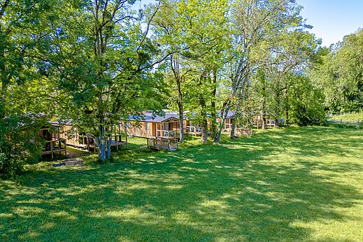 Rij houten stacaravans met schaduwrijke terrassen op camping CLICOCHIC Aloua in Sevrier (74).