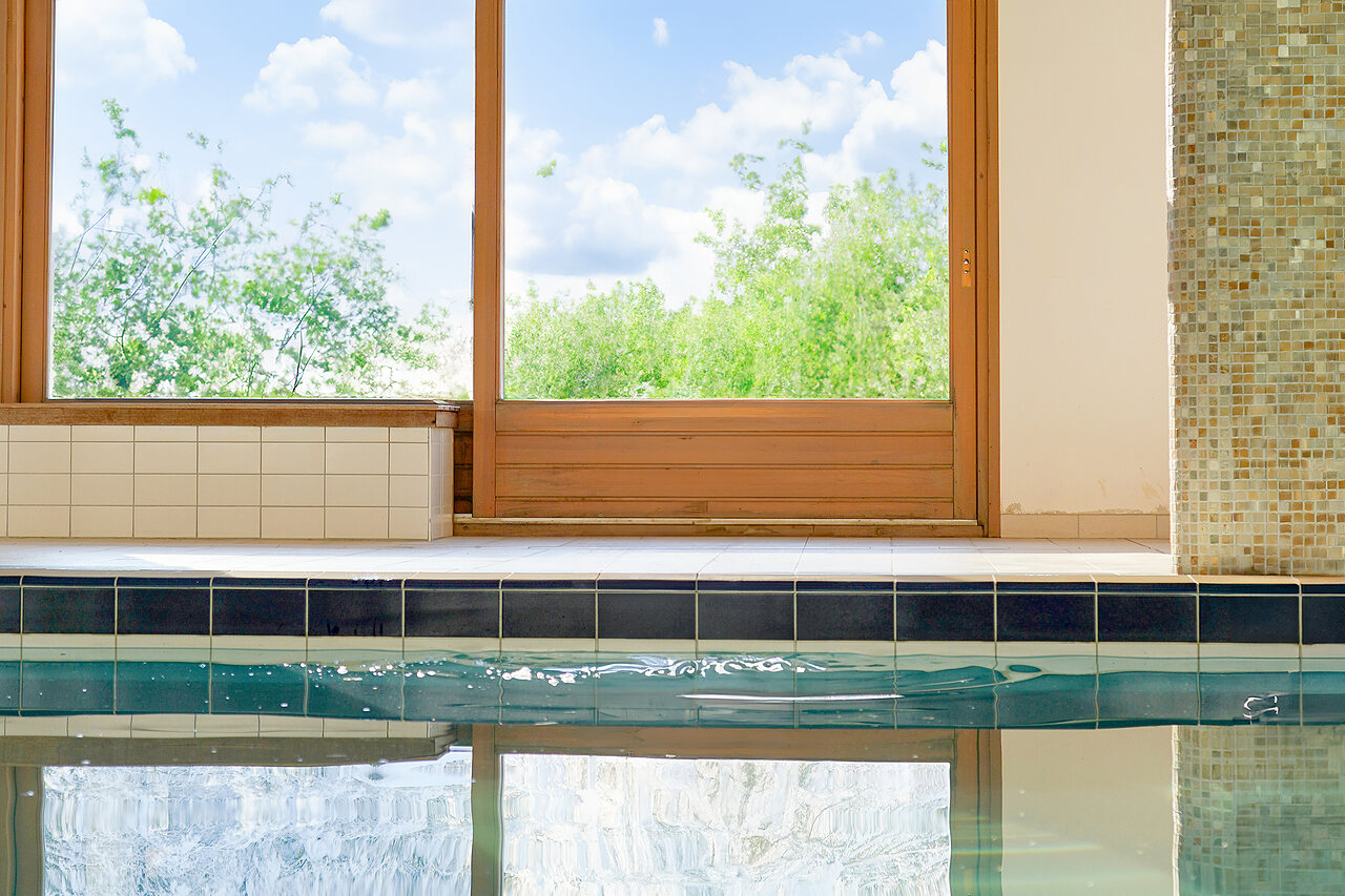 Rand van overdekt zwembad met grote ramen naar de natuur op camping CLICOCHIC Alpes Lodges in Pralognan la Vanoise (73).