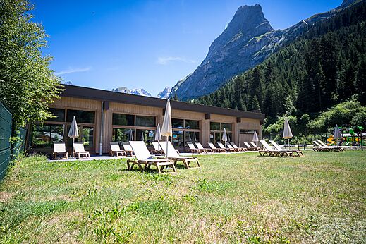 Modern gebouw, stoelen en berguitzicht op camping CLICOCHIC Alpes Lodges.