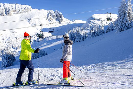 Skiërs op besneeuwde piste, skilift, bergen bij camping CLICOCHIC Alpes Lodges.