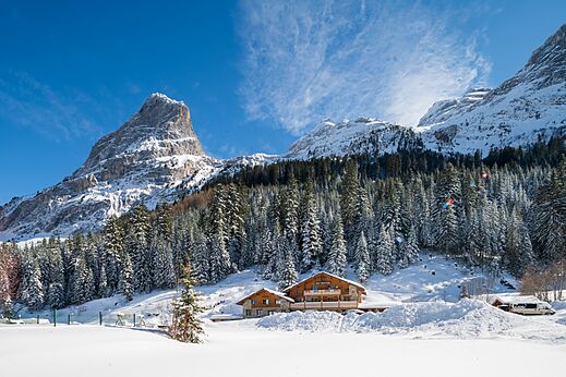 Besneeuwde bergen, houten accommodaties op camping CLICOCHIC Alpes Lodges in Pralognan la Vanoise.