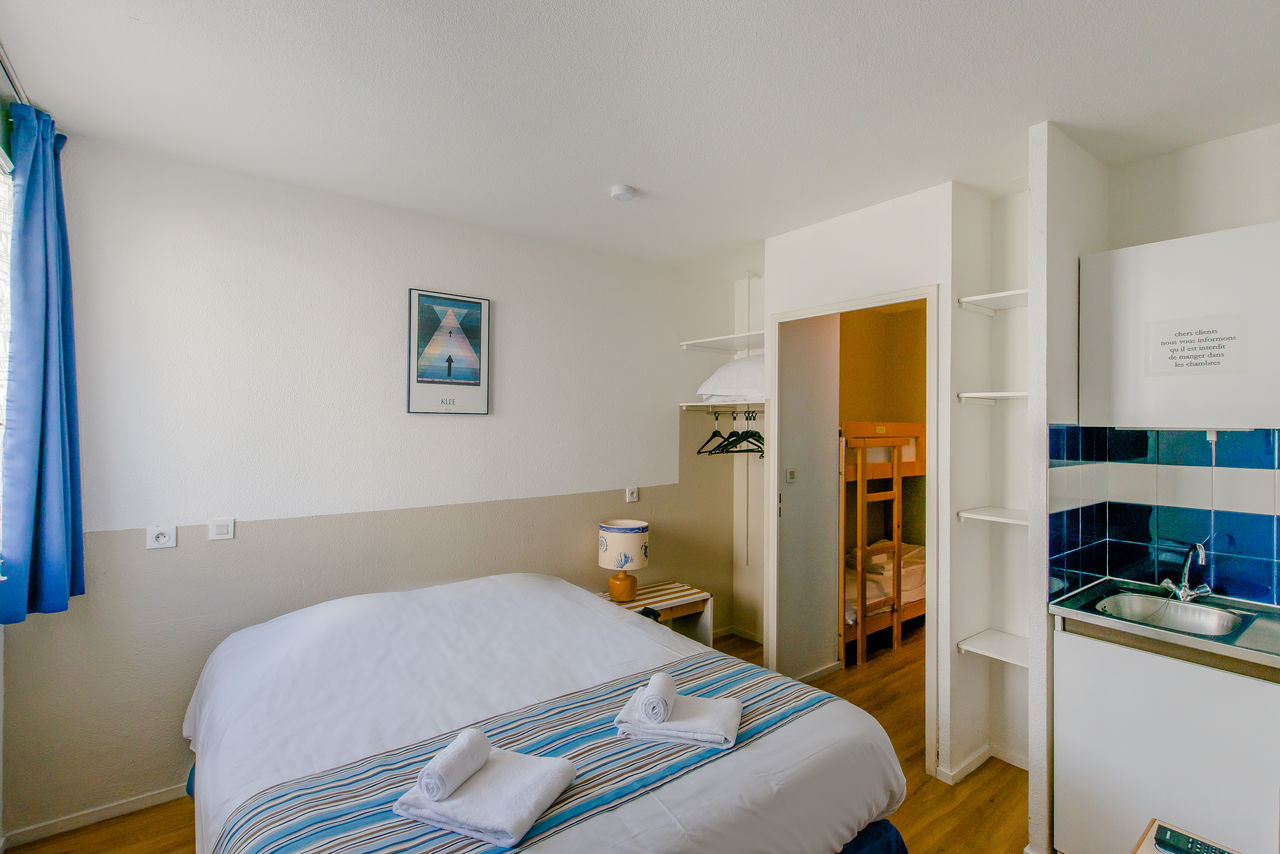 Slaapkamer met tweepersoonsbed, kitchenette, stapelbedden bij CAPFUN H�tel/R�sidence Oc�ane in Andernos.