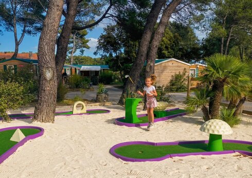 Kleurrijke minigolfbaan met lachend kind op camping CAPFUN Arbois du Castellet in LE CASTELLET (83).