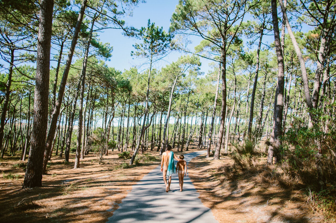 Naturisten wandelend bospad op camping LIBRANOO Naturiste Arnaoutchot, Landes, Frankrijk.
