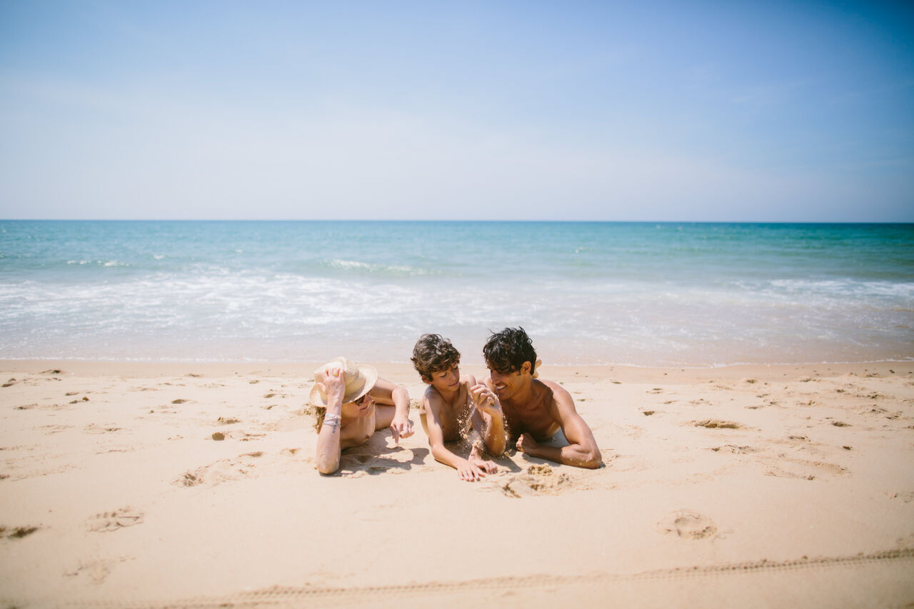 Naturistische familie genietend van het fijne zandstrand op camping LIBRANOO Naturiste Arnaoutchot in Veille-Saint-Girons, Landes, Frankrijk.