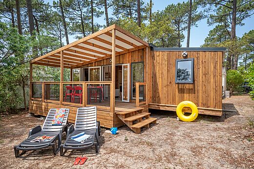 Modern houten stacaravan met overdekt terras op camping LIBRANOO Naturiste Arnaoutchot in Veille-Saint-Girons, Landes, Frankrijk.