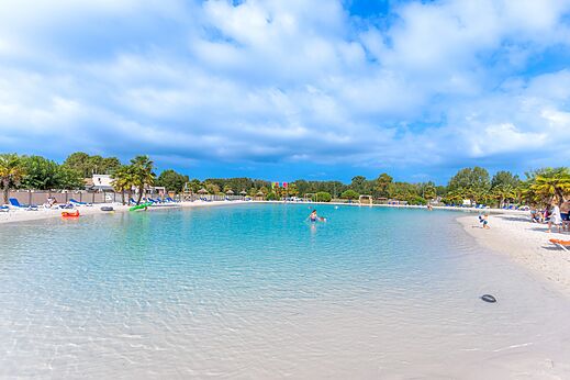 Groot lagunezwembad met zandstrand en palmbomen op camping CAPFUN Atlantique Parc in Les Mathes / La Palmyre (17).