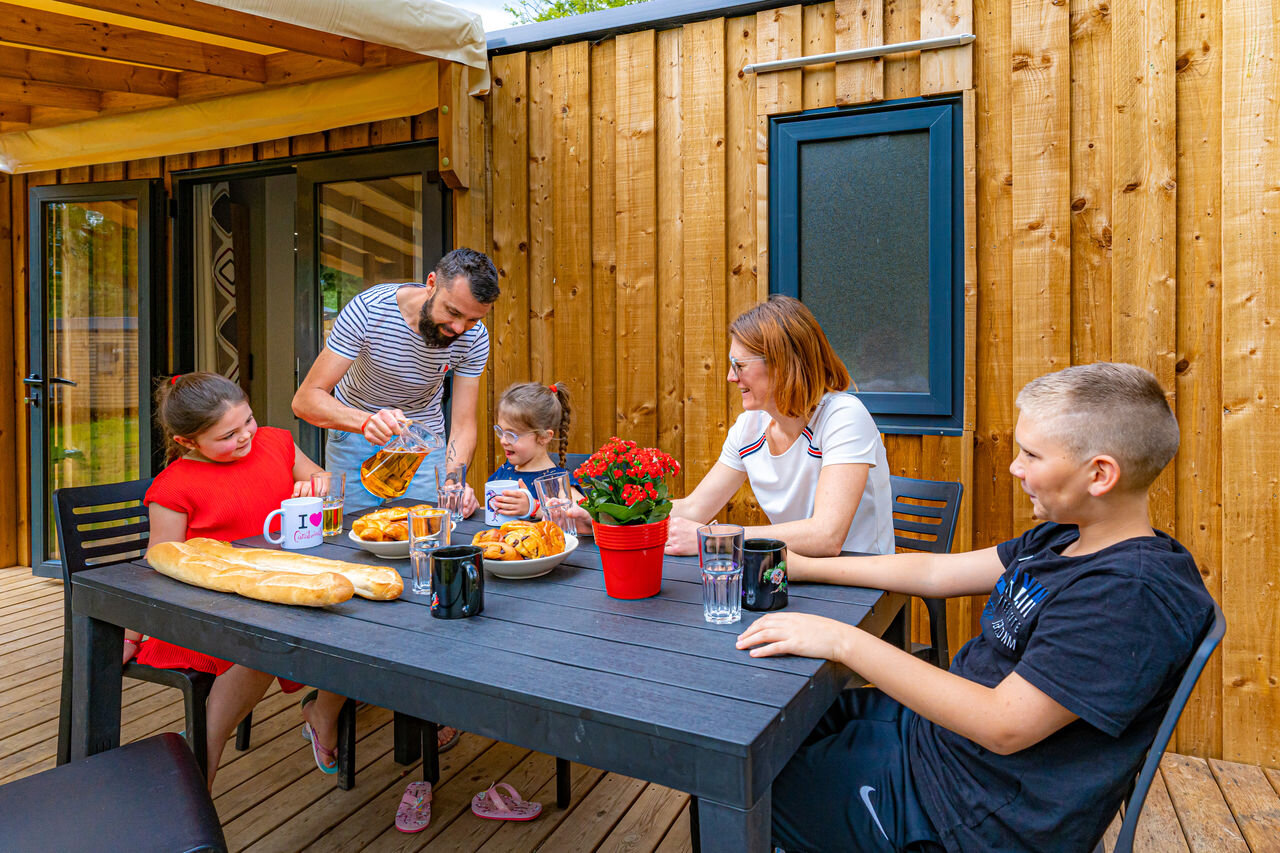 Familie ontbijtend op het terras van een stacaravan, op camping CAPFUN Aube in Deltebre, Tarragona.