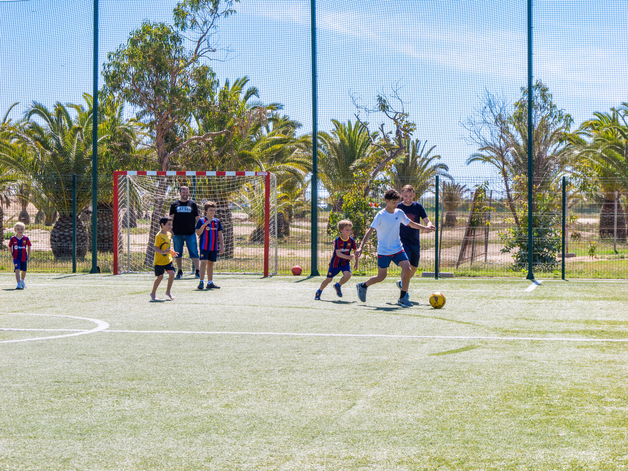 Kinderen voetballen op multisportterrein op camping CAPFUN Aube in Deltebre, Tarragona.