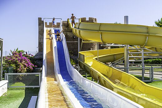 Kleurrijke waterglijbanen met spelende kinderen op camping CAPFUN Aube in Deltebre, Tarragona.