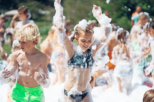Lachende kinderen genieten van schuimfeest op camping CAPFUN Aube in Deltebre, Tarragona.