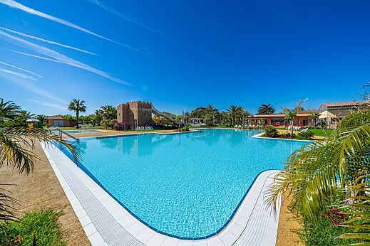 Groot buitenzwembad met glijbaan en palmbomen op camping CAPFUN Aube in Deltebre, Tarragona.