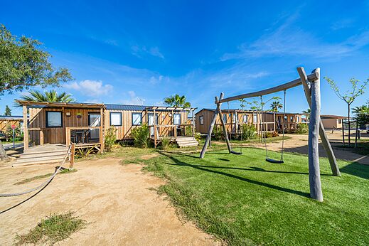 Houten stacaravans met schommels op camping CAPFUN Aube in Deltebre, Tarragona.