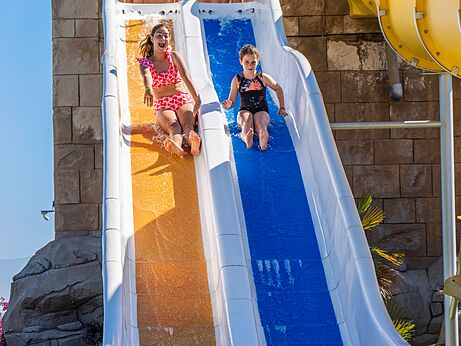 Kinderen glijden van kleurrijke waterglijbaan op camping CAPFUN Aube in Deltebre, Tarragona.