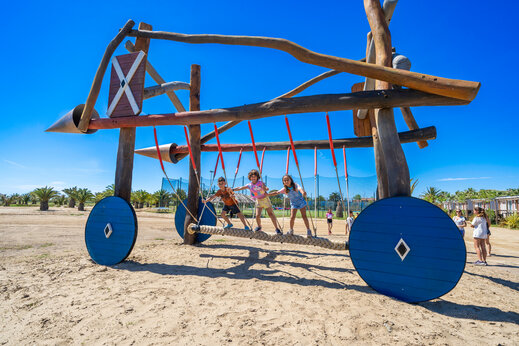 Unieke houten speeltuin met kinderen op touwbrug op camping CAPFUN Aube in Deltebre, Tarragona.