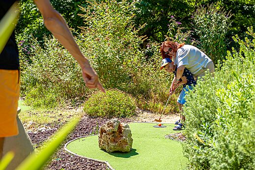 Kind en volwassene spelen minigolf op de baan bij camping CAPFUN Aubr�des in Puget sur Argens (83).