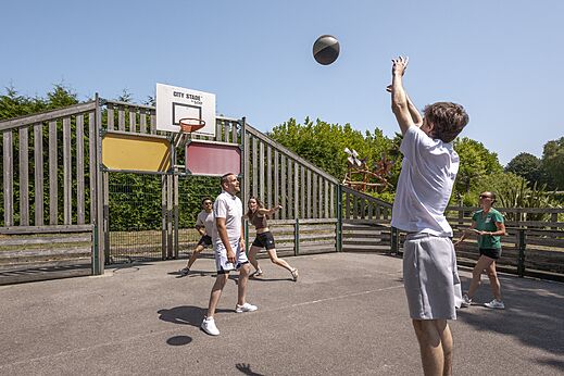 Multisportterrein met vakantiegangers die basketballen op camping CLICOCHIC Baie de Douarnenez in Poullan-sur-Mer.