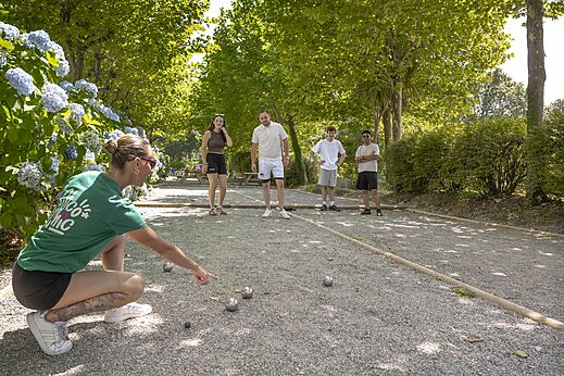 Schaduwrijke jeu-de-boulesbaan met spelers op camping CLICOCHIC Baie de Douarnenez te Poullan-sur-Mer.