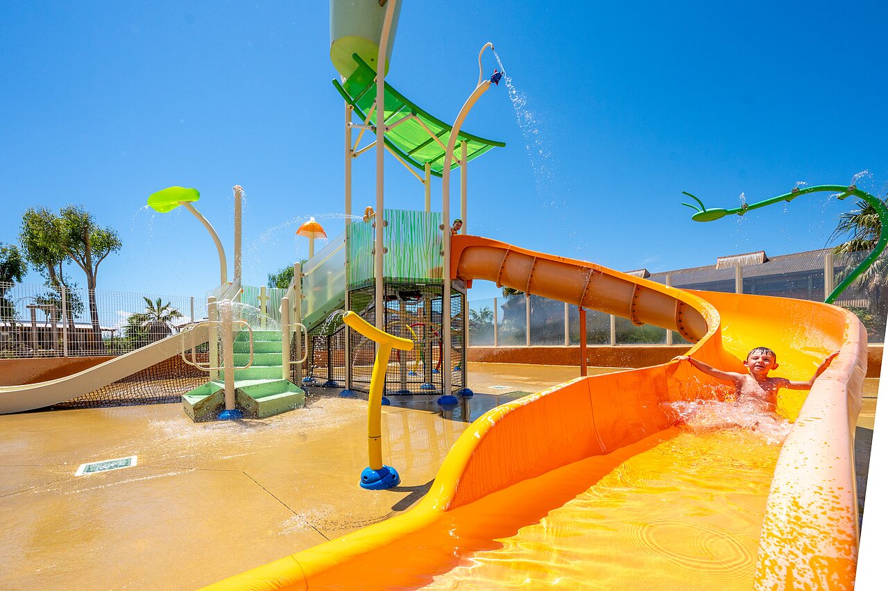 Kind op oranje waterglijbaan, waterspelen op camping CAPFUN Barbacane in NARBONNE (11).