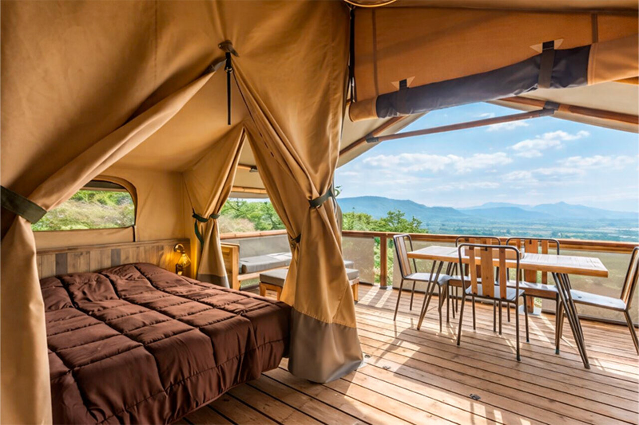 Glamping lodgetent, bed, terras, panoramisch uitzicht op camping CLICOCHIC Bastets.