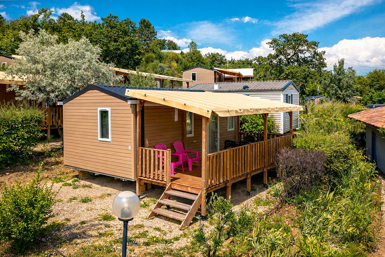 Moderne stacaravan met overdekt terras en roze stoelen op camping CLICOCHIC Bastets in Marsanne (26).