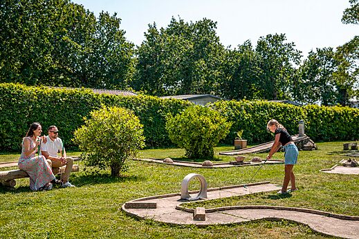 Familie speelt minigolf op een groene baan op camping CLICOCHIC Bastets in Marsanne (26).