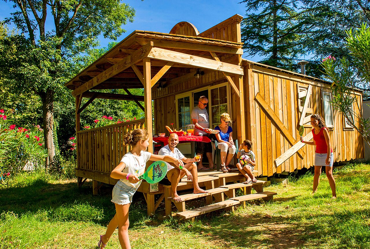 Familie genietend van houten chalet en spelend op camping CAPFUN Bastide in N�mes (30).