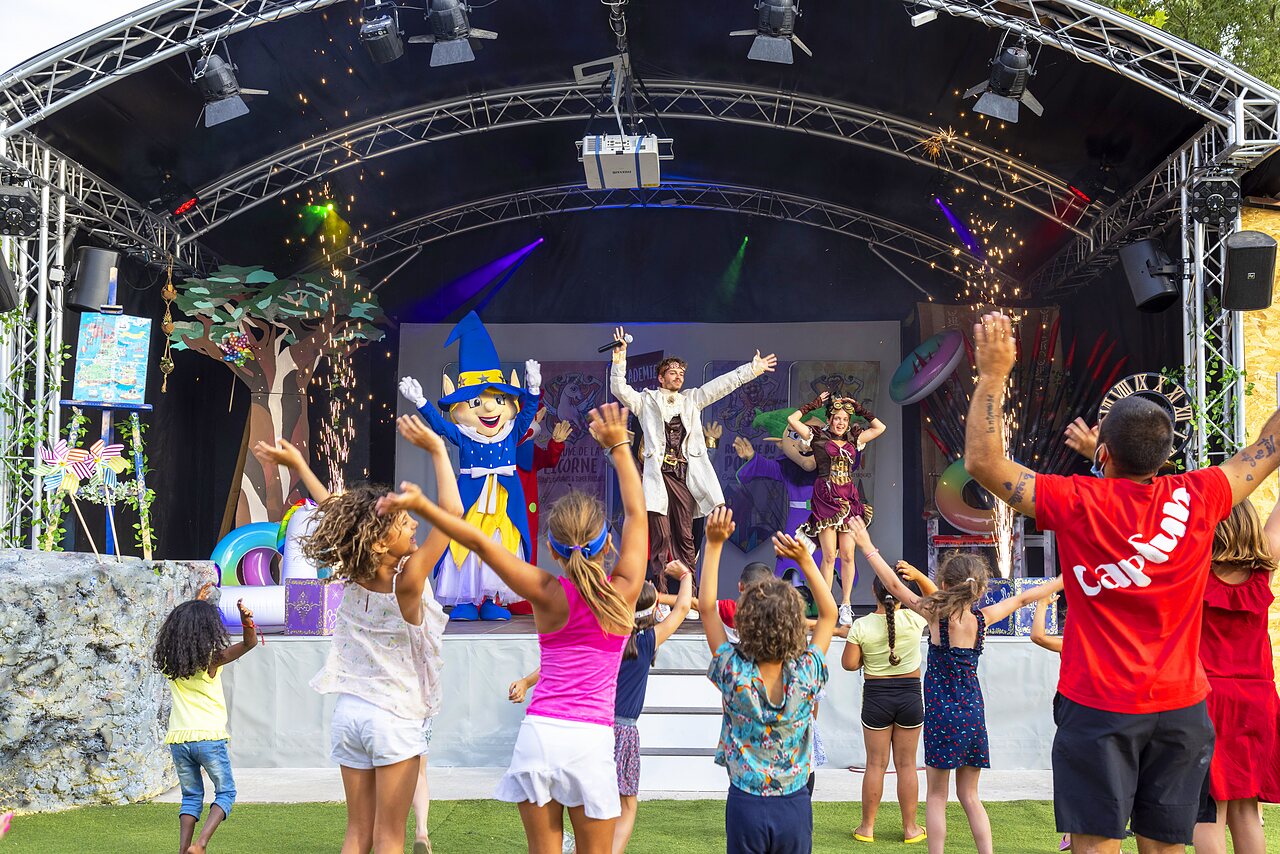 Kinderen dansen voor animatiepodium met mascotte op camping CAPFUN Bastide in N�mes (30).