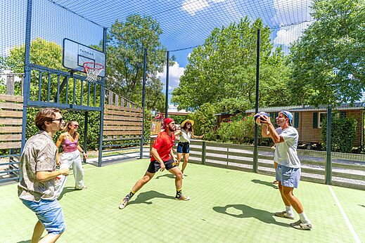 Jongeren spelen basketbal op multisportveld, camping CAPFUN Bastide in Nîmes (30).