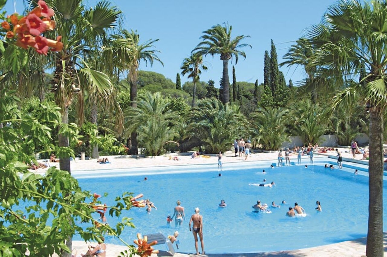 Buiten zwembad lagune met palmbomen en zwemmers op camping CAPFUN La Baume - La Palmeraie in Fr�jus (83).