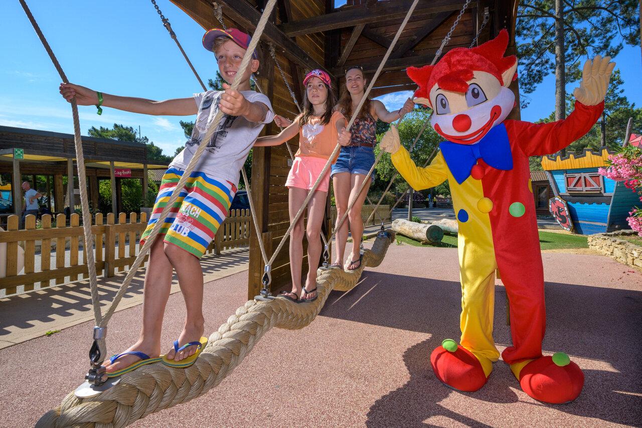 Kinderen spelen op touwbrug met mascotte op camping CAPFUN Beauregard in MORNAS (84).