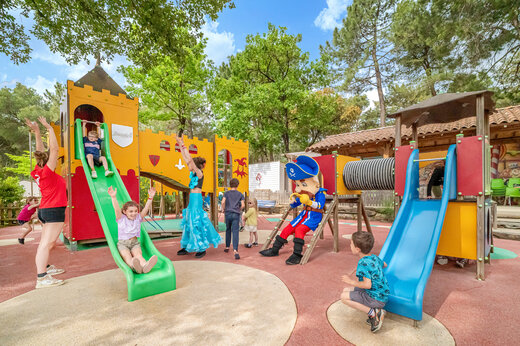 Speeltuin met glijbanen, kinderen en mascotte op camping CAPFUN Beauregard in MORNAS (84).