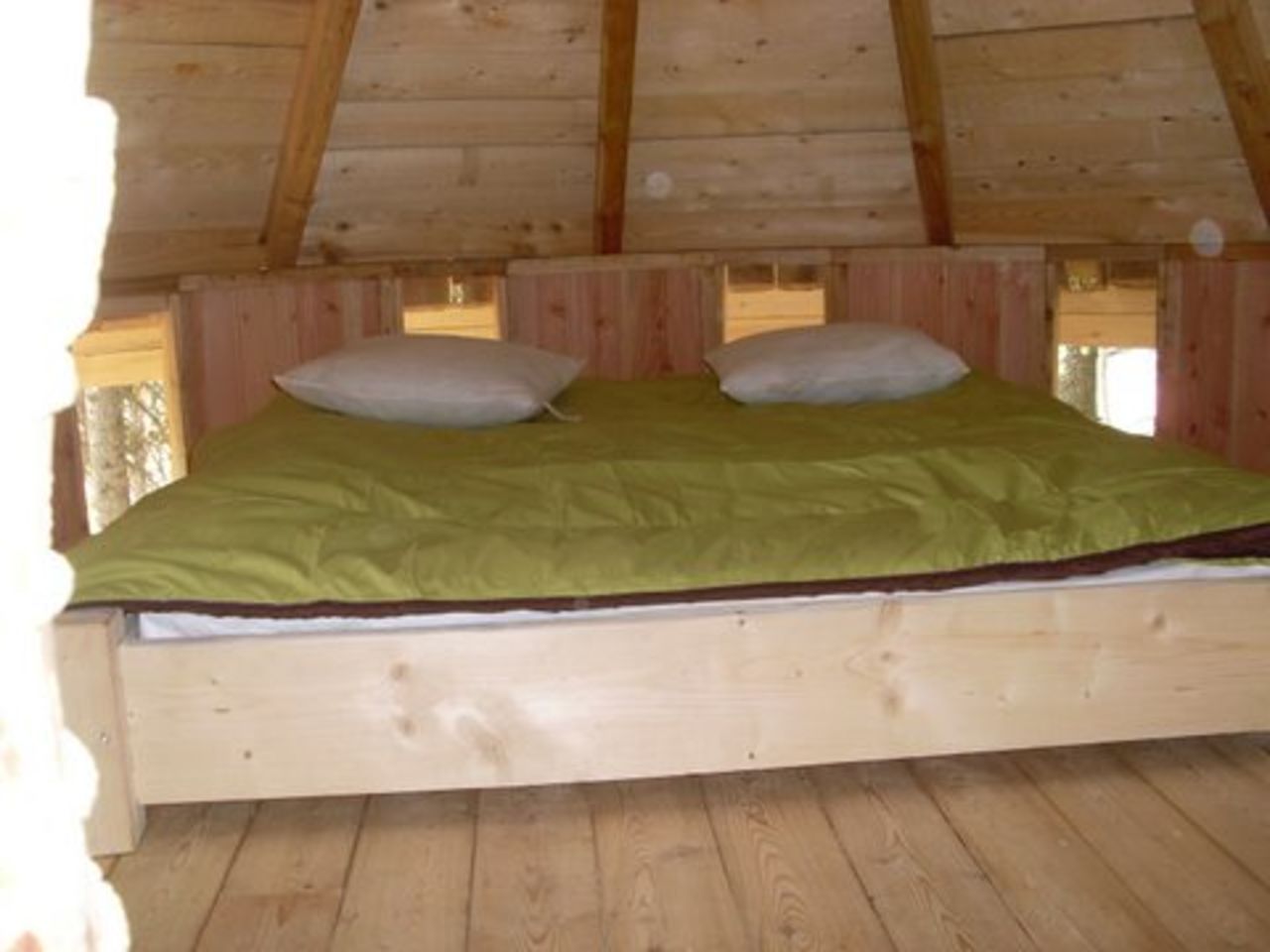 Houten tweepersoonsbed, groen dekbed, hut bij CAPFUN Beauregard, Mornas (84).