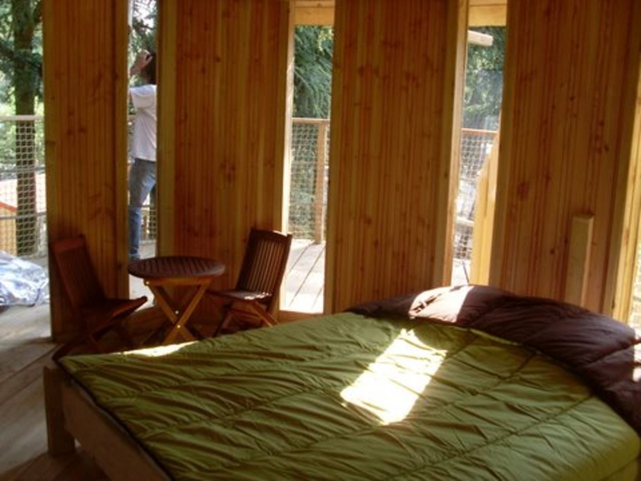 Interieur boomhut, bed, tafel, stoelen op camping CAPFUN Beauregard.
