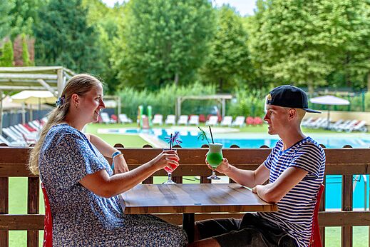 Lachend stel met cocktails aan de zwembadbar, op camping CLICOCHIC Beau Rivage in LA ROQUE-GAGEAC (24).