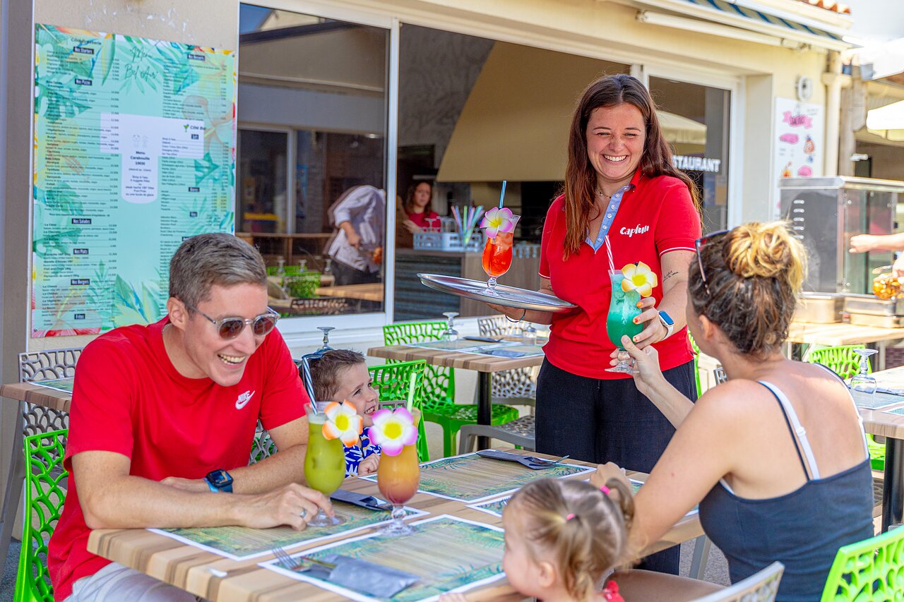 Familie geniet van kleurrijke cocktails op restaurantterras op camping CAPFUN Bel Air in Aiguillon sur Mer (85).
