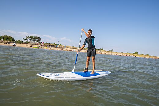 Jongere op paddleboard en strand bij camping CAPFUN Bel Air in Aiguillon sur Mer (85).