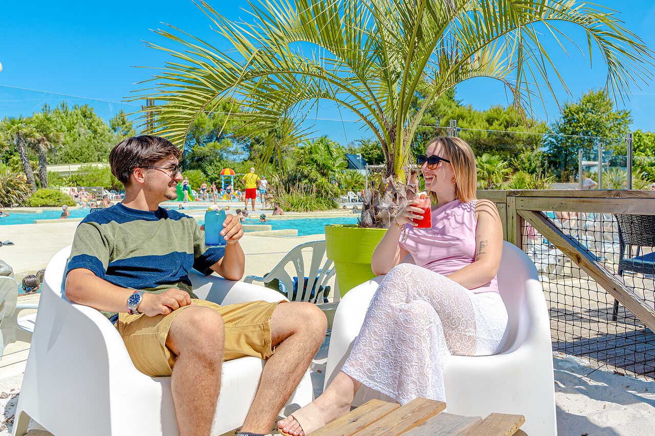 Paar met cocktails bij het zwembad op camping VAGUES OCEANES Blancs Ch�nes in LA TRANCHE SUR MER.