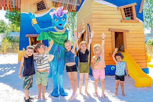 Mascotte en kinderen op de speeltuin van camping VAGUES OCEANES Blancs Chênes.