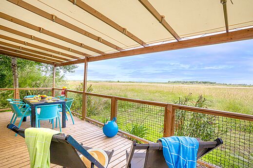 Overdekt terras van accommodatie met eettafel en uitzicht op de natuur op camping VAGUES OCEANES Blancs Chênes in LA TRANCHE SUR MER (85).