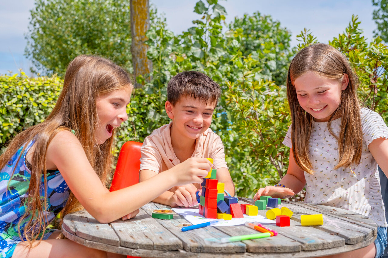 Lachende kinderen spelen met kleurrijke bouwblokken op camping VAGUES OCEANES Bois Joly.