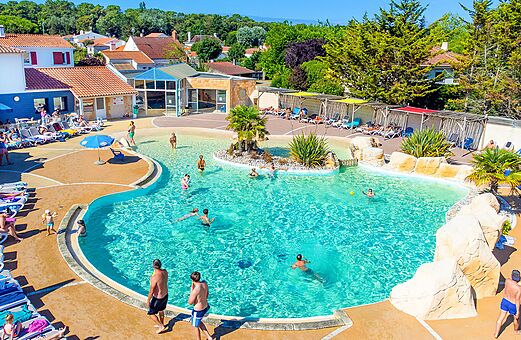 Groot buitenzwembad met ondergedompeld strand en stoelen op camping VAGUES OCEANES Bois Joly in Saint-Jean-de-Monts (85).