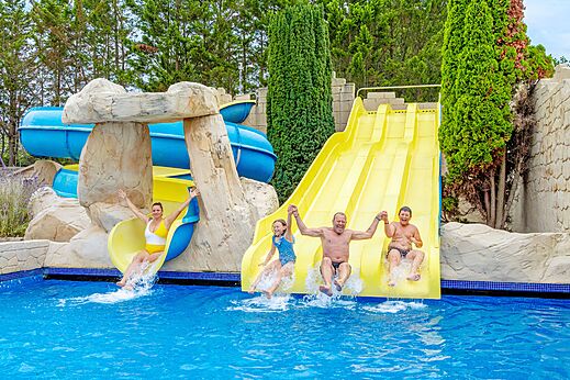 Familie op waterglijbanen en buitenzwembad op camping VAGUES OCEANES Bois Joly in Saint-Jean-de-Monts.