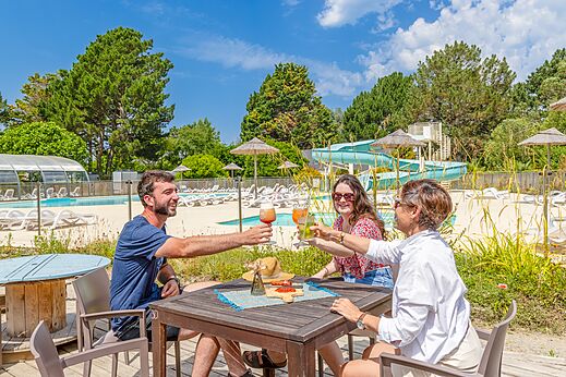 Familie proostend aan de bar, zwembad en glijbaan camping CLICOCHIC Bordénéo Belle-Île.