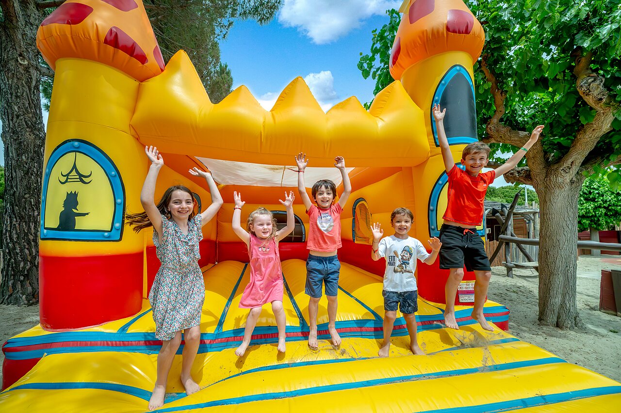 Opblaasbaar kasteel en blije kinderen op camping CAPFUN Boucanet in LE GRAU DU ROI (30).