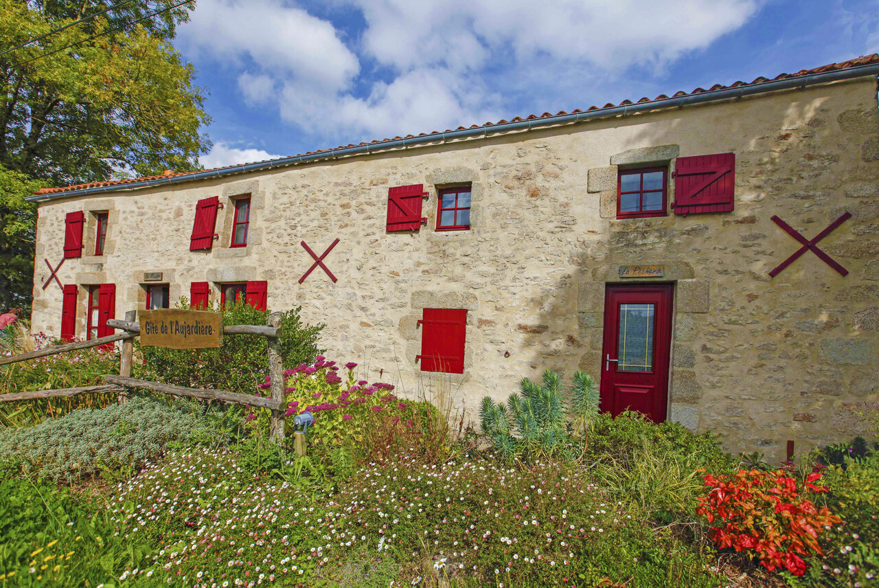 Stenen g�te, rode luiken, bloemrijke tuin op camping CAPFUN Breteche, Les Epesses.