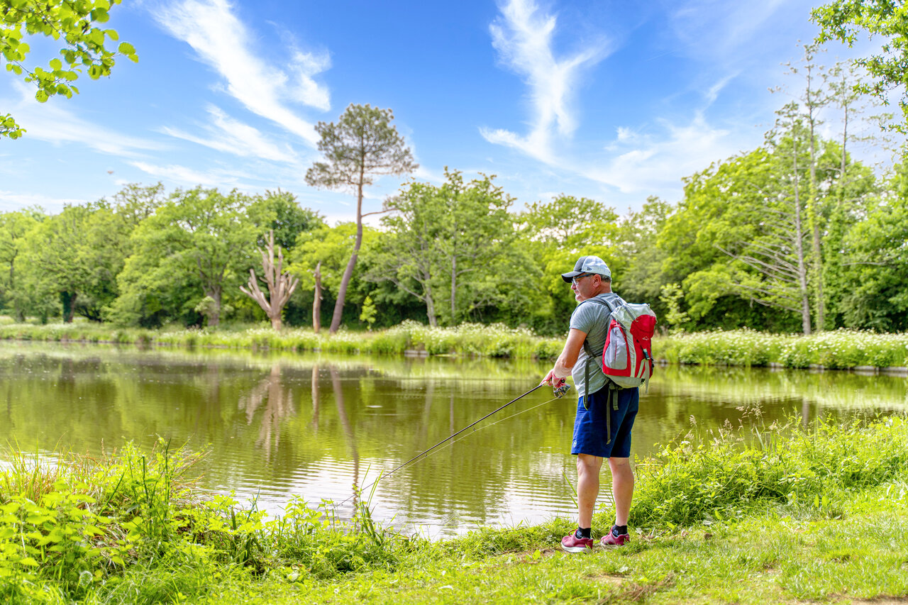 Visser aan de groene oever van het meer op camping CAPFUN Breteche in Les Epesses.