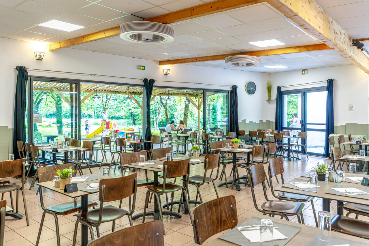 Lichte restaurantzaal met uitzicht op de speeltuin op camping CAPFUN Breteche in Les Epesses (85).
